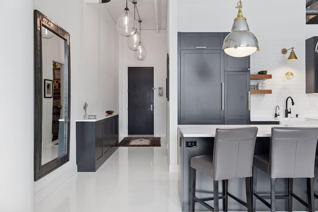 kitchen featuring a breakfast bar, open shelves, decorative backsplash, and decorative light fixtures