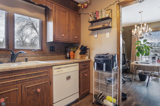 kitchen featuring white dishwasher, sink, dark hardwood / wood-style flooring, and hanging light fixtures