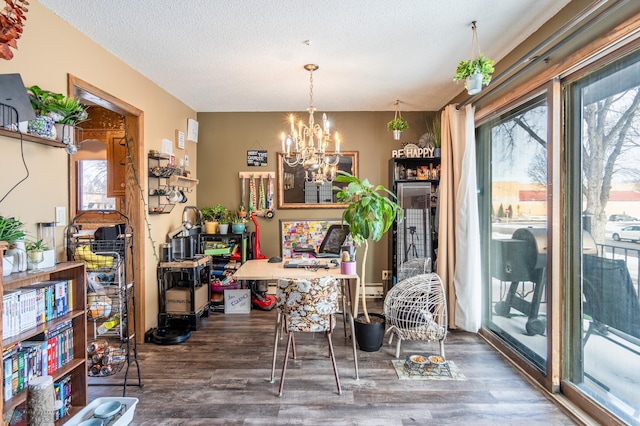 dining area with dark wood-type flooring, an inviting chandelier, and a textured ceiling