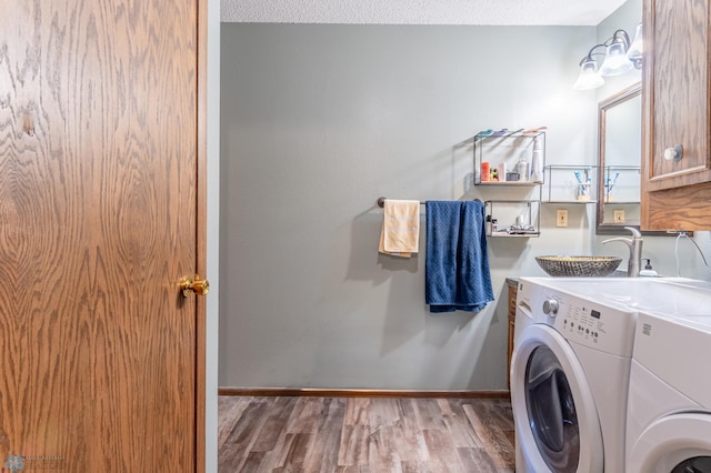 laundry area featuring cabinets, light wood-type flooring, washer and dryer, and a textured ceiling