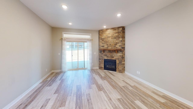 unfurnished living room with a stone fireplace and light hardwood / wood-style floors