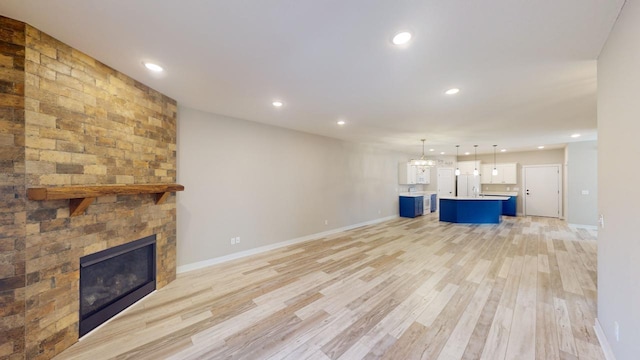 unfurnished living room featuring a notable chandelier, a large fireplace, and light wood-type flooring