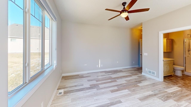 interior space featuring ceiling fan, ensuite bathroom, and light wood-type flooring