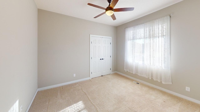 empty room featuring light colored carpet and ceiling fan