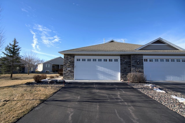 ranch-style home featuring driveway, stone siding, and an attached garage