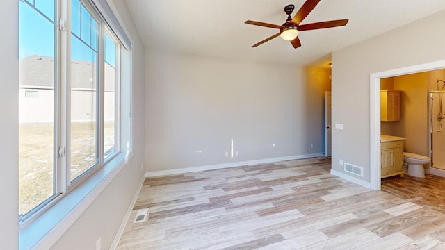 unfurnished bedroom with light wood finished floors, baseboards, and ensuite bathroom