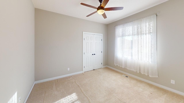 carpeted spare room featuring ceiling fan and baseboards