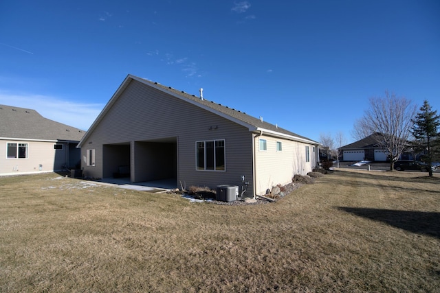 rear view of house featuring central AC unit, a garage, a lawn, and a patio