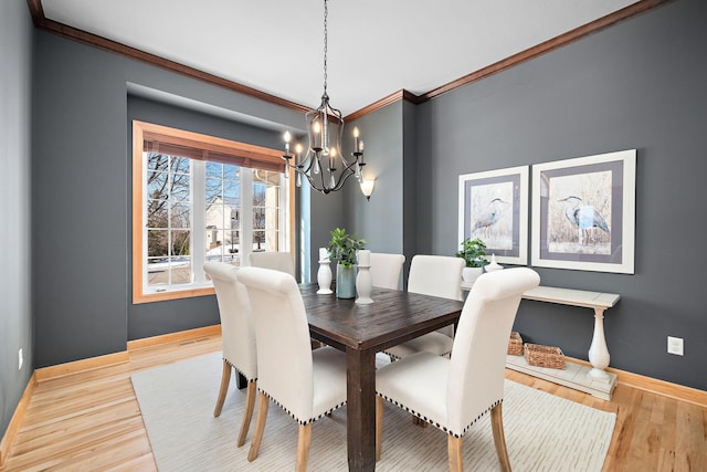 dining space featuring a chandelier, ornamental molding, light wood-type flooring, and baseboards