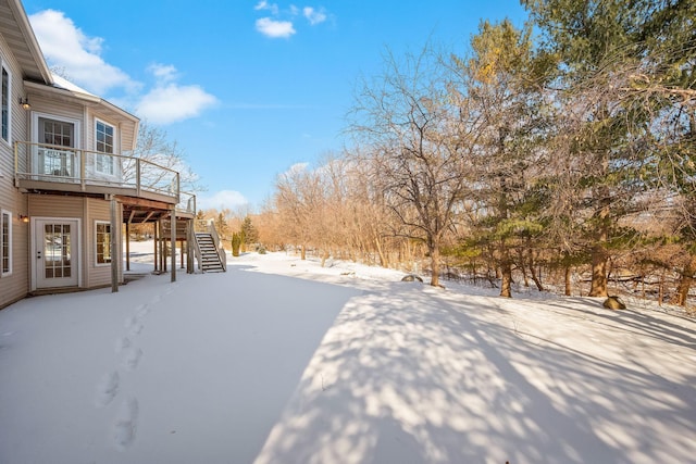 snowy yard with stairs and a wooden deck