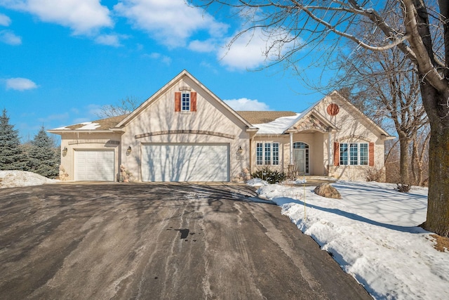 view of front facade with a garage, stone siding, aphalt driveway, and stucco siding