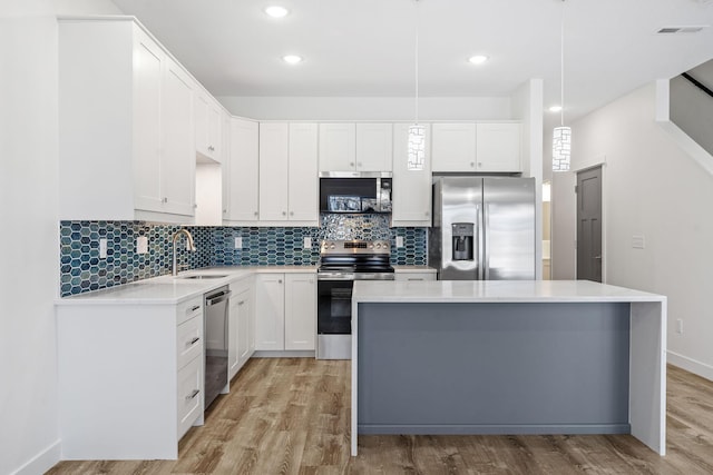 kitchen with pendant lighting, sink, white cabinets, a center island, and stainless steel appliances