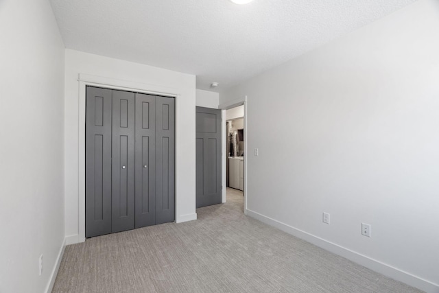 unfurnished bedroom featuring light colored carpet, a closet, and a textured ceiling