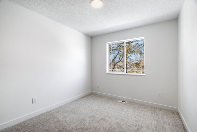 carpeted empty room featuring a textured ceiling