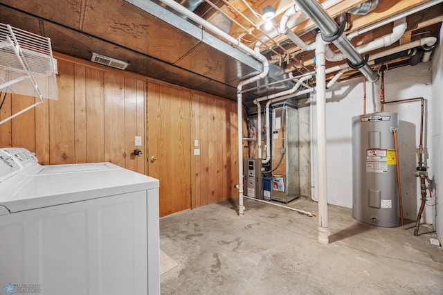 basement featuring separate washer and dryer, electric water heater, and wood walls