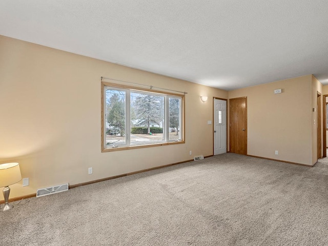 unfurnished room featuring carpet floors, baseboards, visible vents, and a textured ceiling