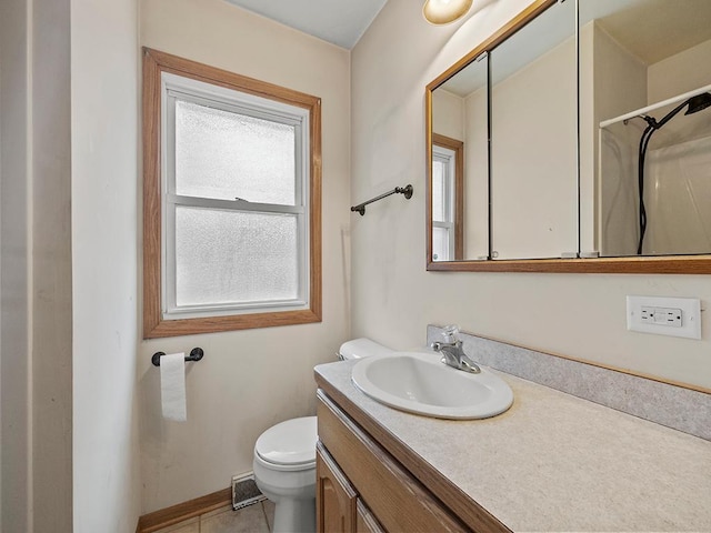 bathroom with visible vents, toilet, vanity, baseboards, and walk in shower