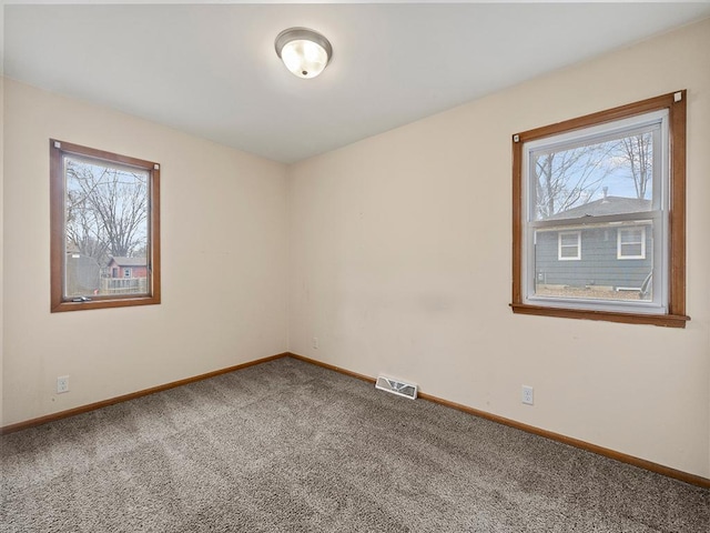 spare room with carpet, visible vents, and baseboards