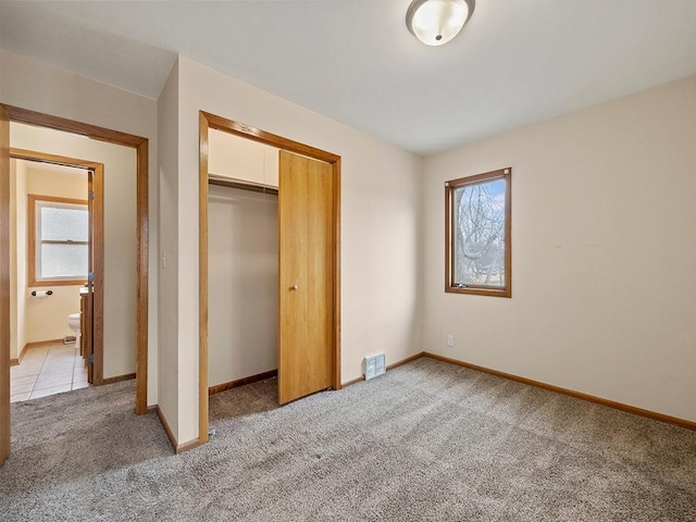 unfurnished bedroom featuring a closet, visible vents, light carpet, and baseboards