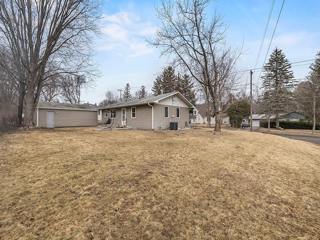 back of property with cooling unit, a lawn, and an outbuilding