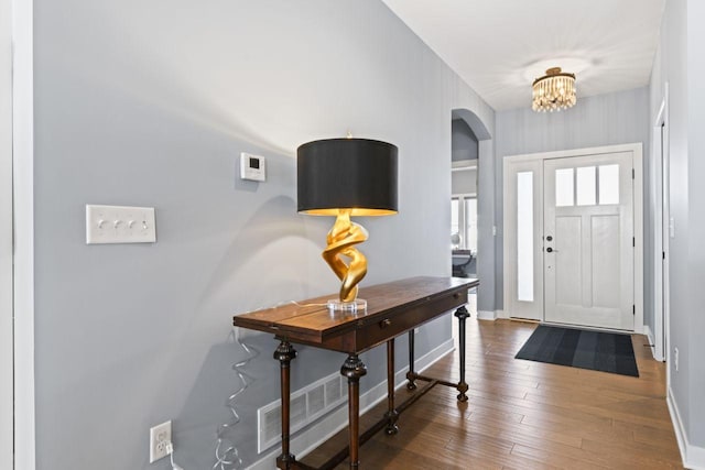 foyer entrance with an inviting chandelier and dark hardwood / wood-style floors