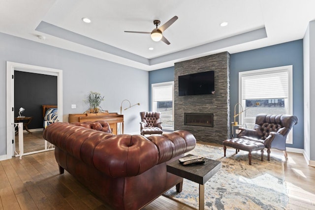 living room with ceiling fan, a fireplace, dark hardwood / wood-style flooring, and a raised ceiling