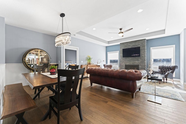 dining area featuring a raised ceiling, a healthy amount of sunlight, and a fireplace