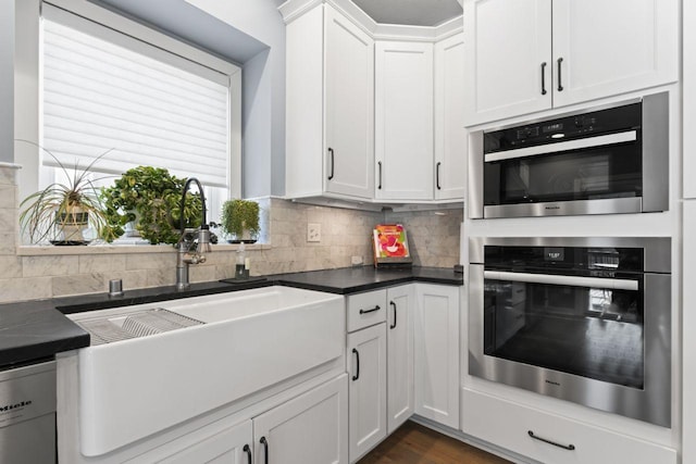 kitchen with double oven, white cabinetry, sink, decorative backsplash, and white dishwasher