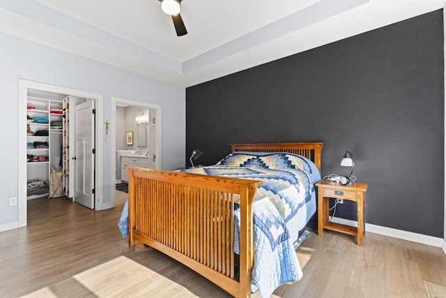 bedroom with ceiling fan, wood-type flooring, a spacious closet, and a closet