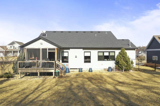 rear view of property featuring a sunroom, a deck, and a lawn