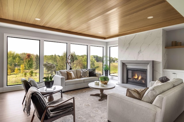 living room featuring light hardwood / wood-style flooring, wood ceiling, and a fireplace