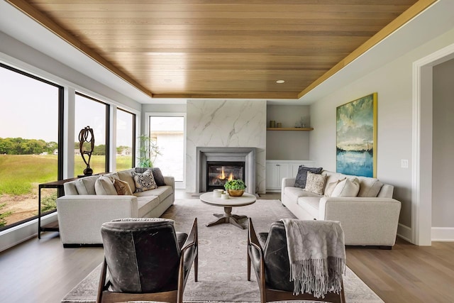 living room with a tray ceiling, wood ceiling, and light hardwood / wood-style flooring