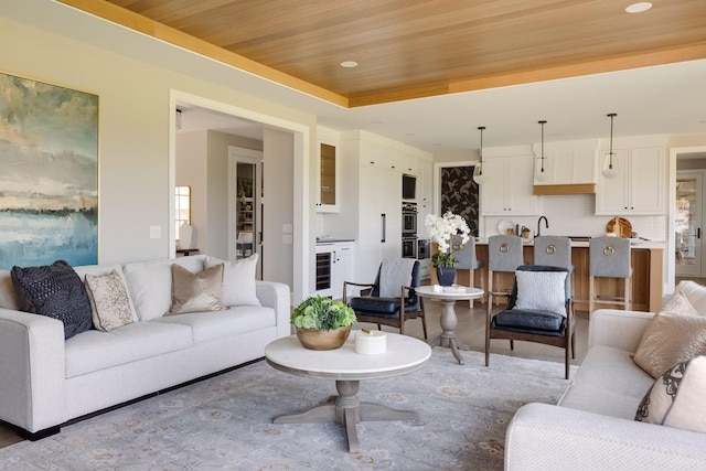 living room with a raised ceiling, sink, wine cooler, and wood ceiling