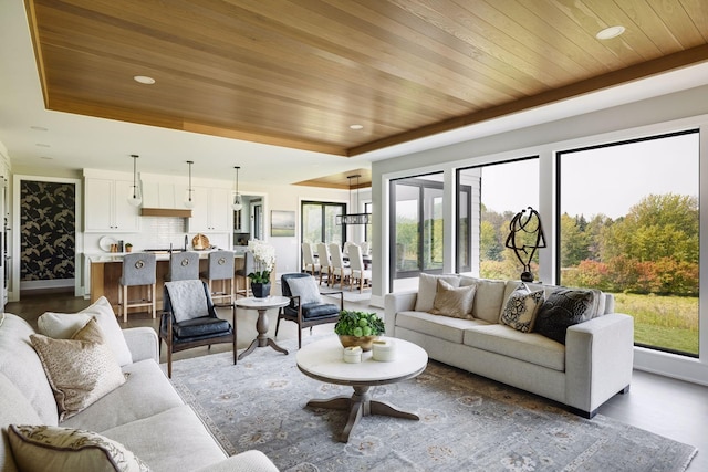 living room with a tray ceiling, wooden ceiling, and dark hardwood / wood-style floors