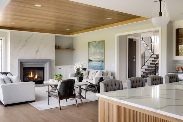 living room featuring wood ceiling, a premium fireplace, a raised ceiling, and hardwood / wood-style flooring