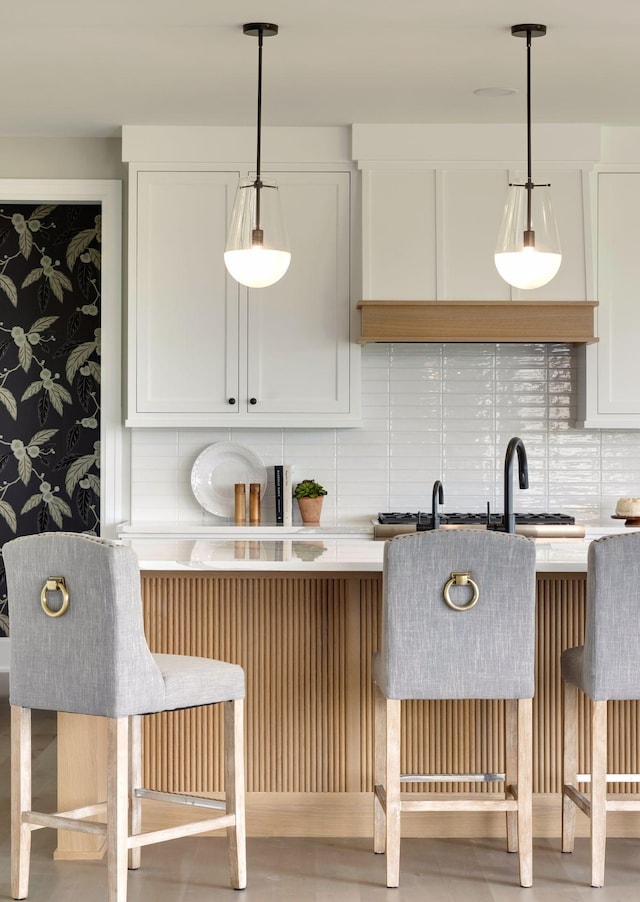 interior space with white cabinetry, a kitchen breakfast bar, and hanging light fixtures