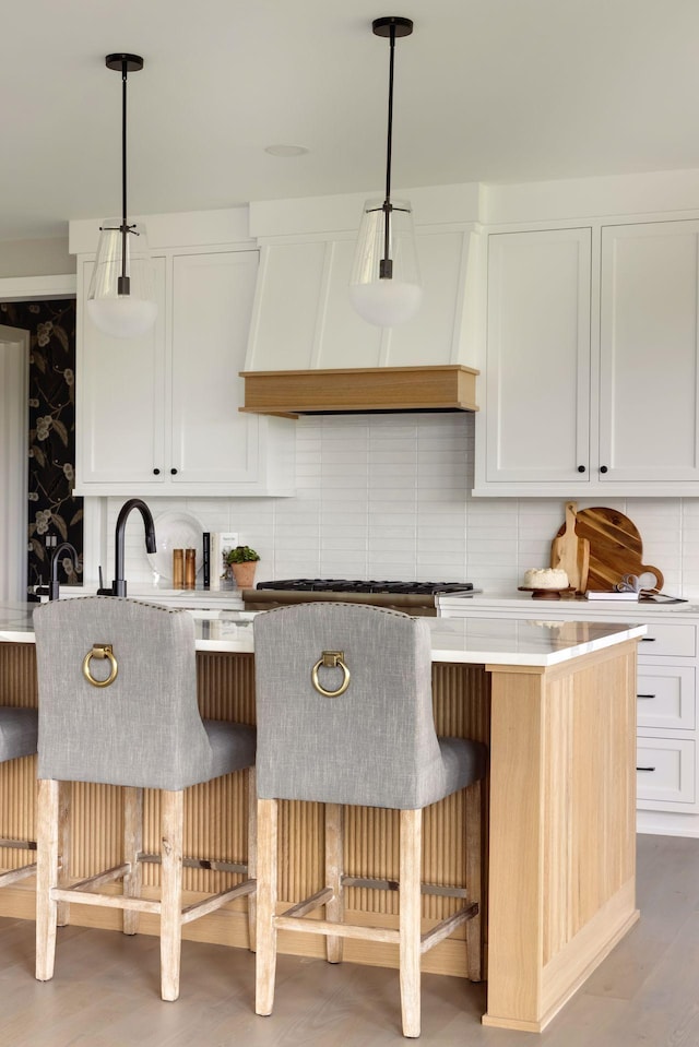 kitchen featuring premium range hood, white cabinetry, gas cooktop, and hanging light fixtures