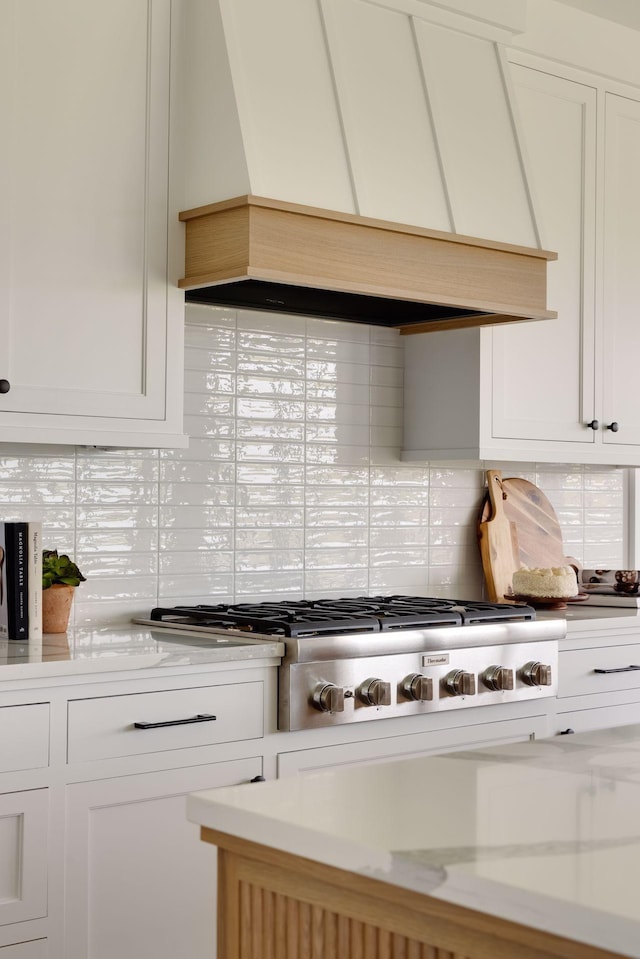 kitchen with white cabinetry, backsplash, and custom range hood