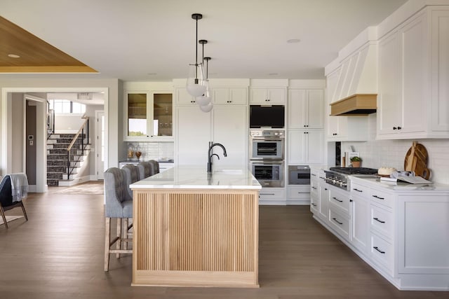 kitchen featuring sink, white cabinetry, a center island with sink, appliances with stainless steel finishes, and a kitchen breakfast bar