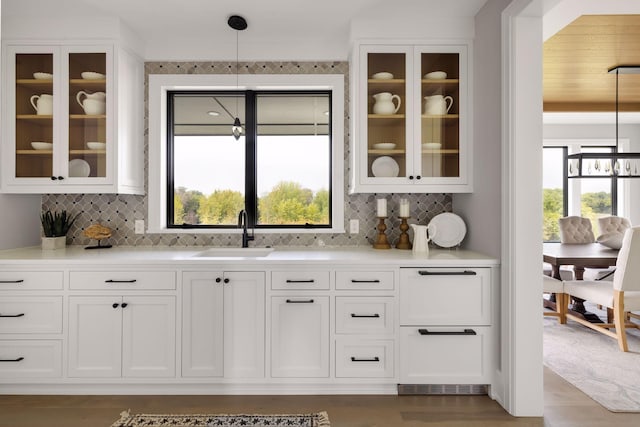 bar featuring sink, white cabinetry, an inviting chandelier, decorative light fixtures, and backsplash