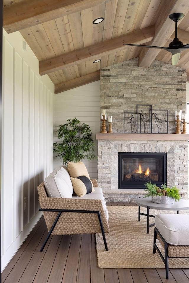 living room with wood ceiling, wood-type flooring, a stone fireplace, and lofted ceiling with beams