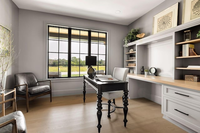 office space with built in desk and light hardwood / wood-style flooring