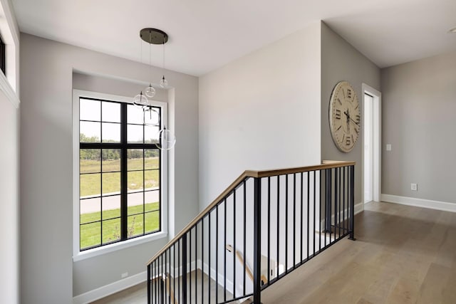 staircase with hardwood / wood-style floors and an inviting chandelier