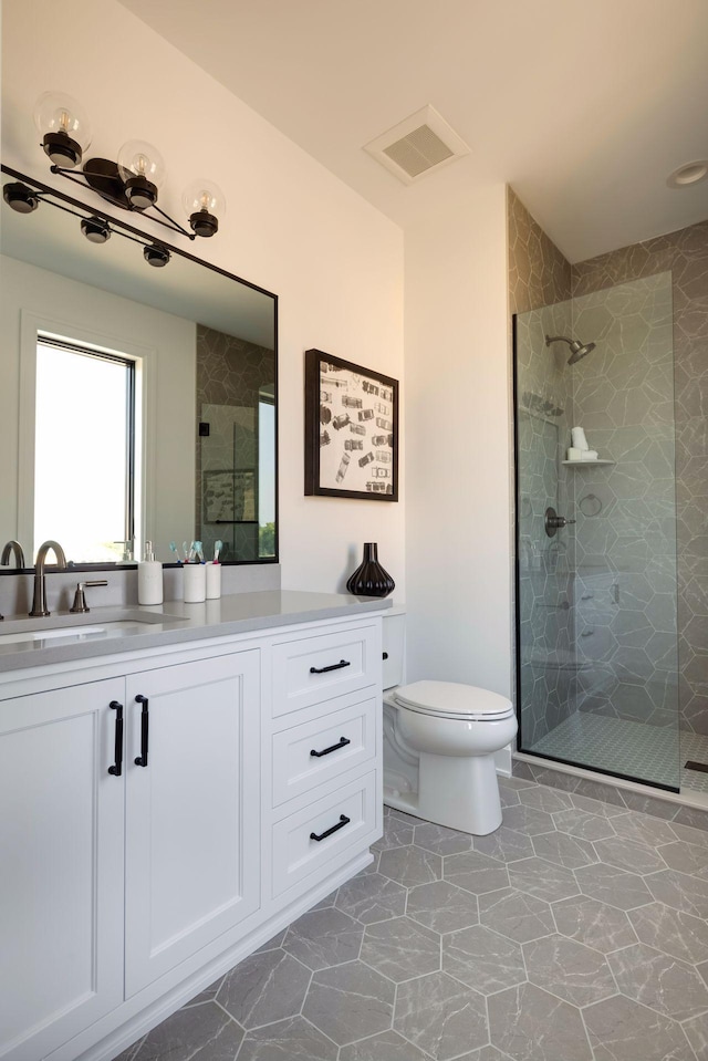 bathroom with vanity, a shower with door, and toilet