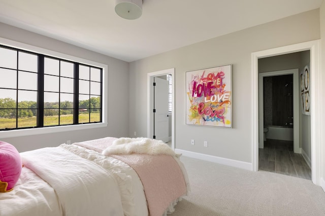 bedroom with ensuite bathroom and light colored carpet