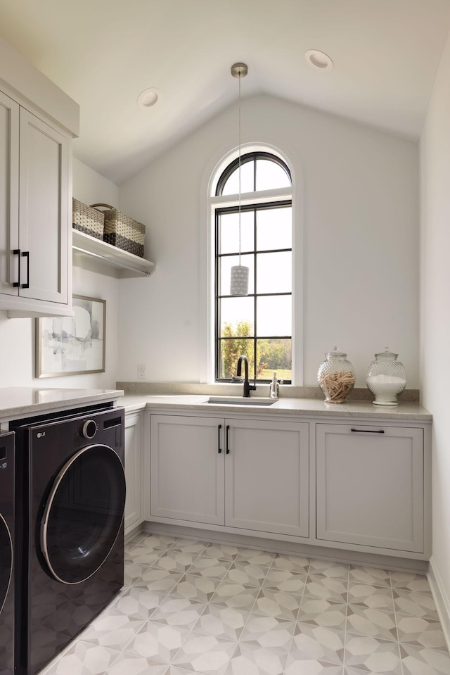 clothes washing area with cabinets, washing machine and dryer, and sink