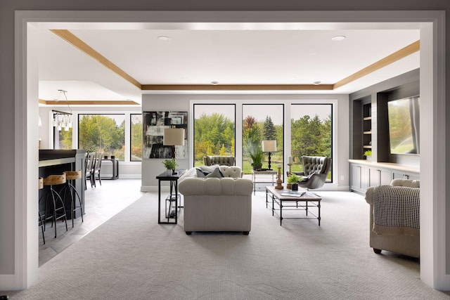 carpeted living room featuring a tray ceiling and a notable chandelier