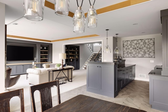 kitchen featuring built in shelves, decorative light fixtures, and gray cabinetry