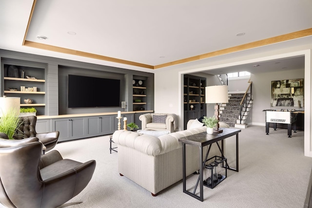 living room featuring a raised ceiling, light carpet, and built in features