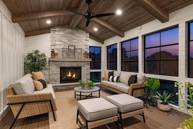 sunroom / solarium featuring lofted ceiling with beams, ceiling fan, wood ceiling, and an outdoor stone fireplace